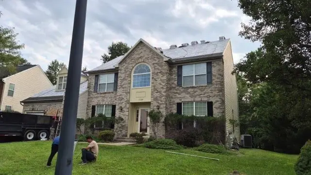 Brick colonial home mid roof replacement with underlayment down and shingle bundles staged on the roof