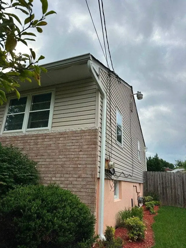 Close-up of new vinyl siding and gutter corner detail against brick